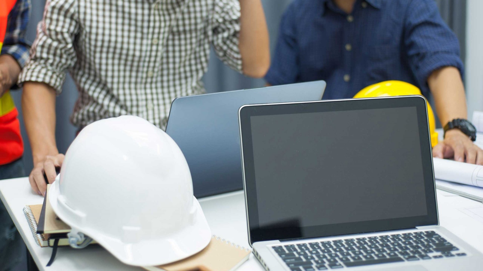 two workers looking at laptops on a table